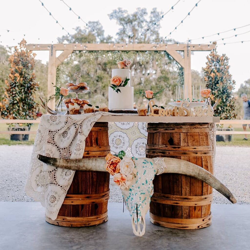 cake and dessert table set up for wedding on top of large barrels with skull and flowers in front